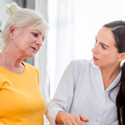 A caregiver talking to a resident in a bright room