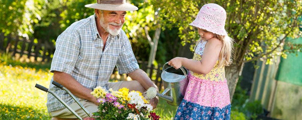 Elderly man gardening with a young girl