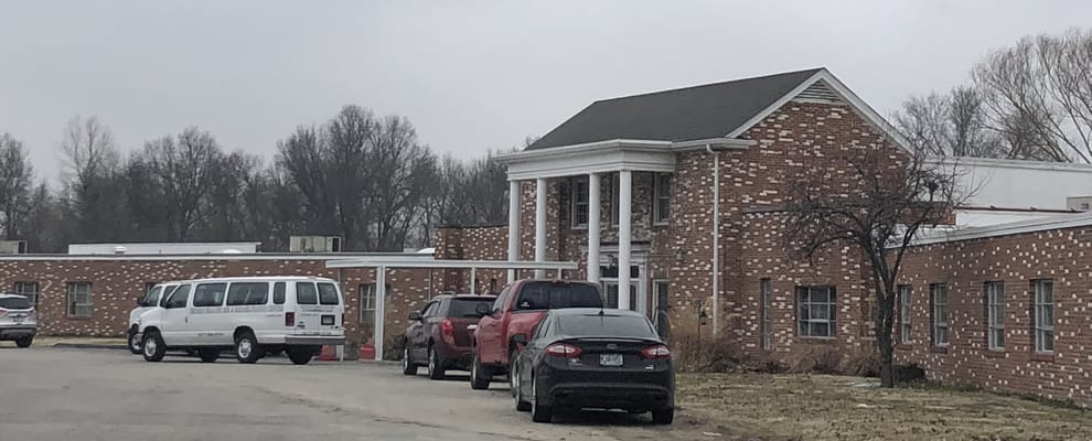 Exterior view of a nursing home facility with vehicles