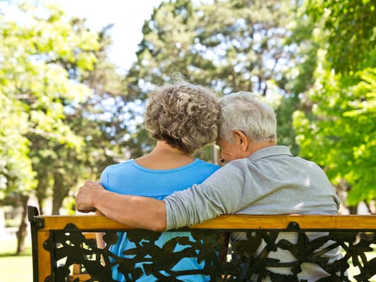 Two seniors enjoying a sunny day on a bench