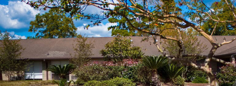 Exterior view of a senior living facility surrounded by gardens