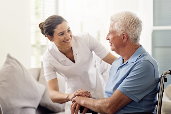 Nurse assisting a senior man in a bright living area