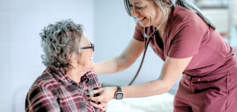 A caregiver smiling while checking a resident's heart rate