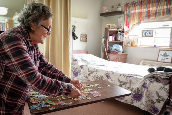 Resident working on a jigsaw puzzle in her room