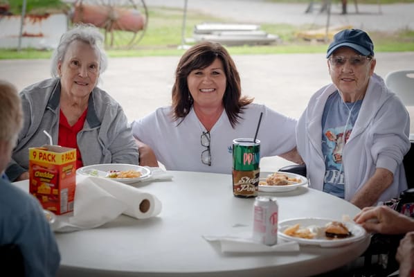Residents enjoying a meal outdoors with staff
