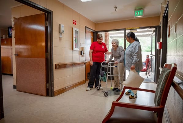 Staff assisting resident in a facility hallway