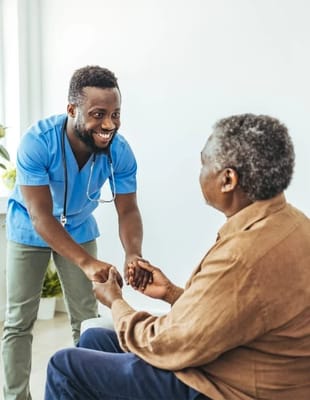 Caregiver smiling and holding hands with senior resident