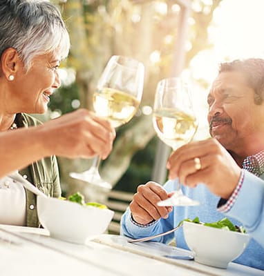 Couple enjoying a meal outdoors, toasting with glasses of wine
