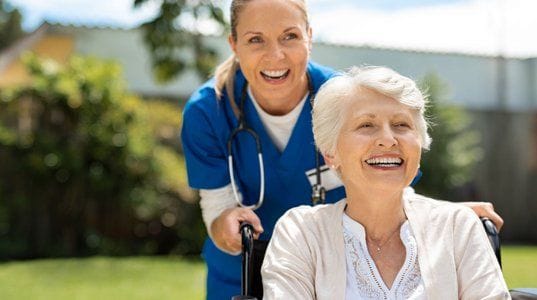 A caregiver and resident smiling in a garden