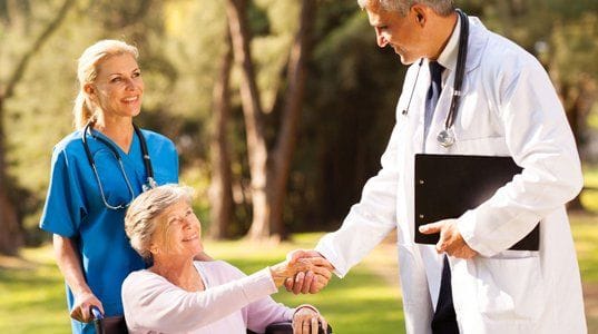 A doctor and nurses interacting with a resident outdoors