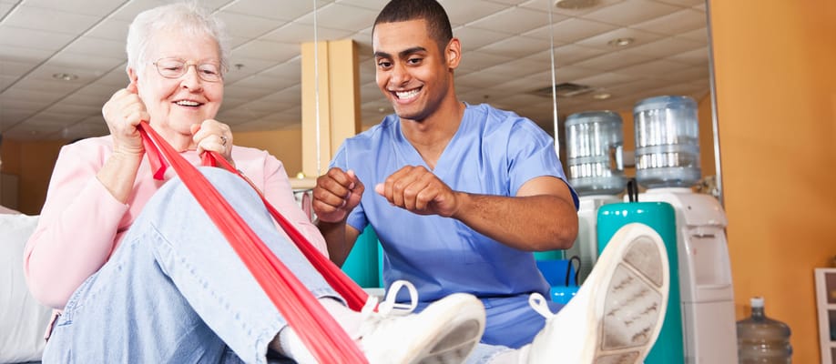 Resident exercising with staff assistance in a therapy room
