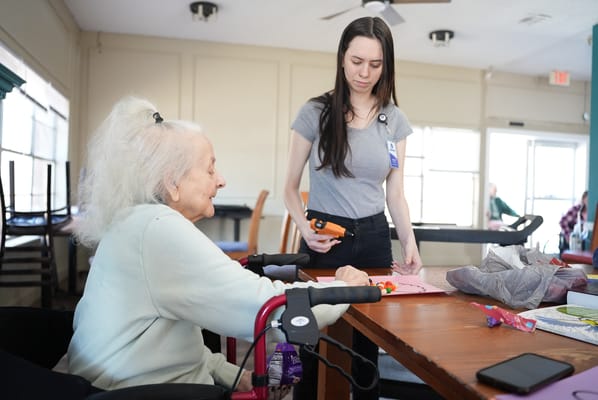 Resident engaged in a craft activity with staff assistance