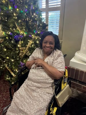 Resident smiling by a decorated Christmas tree