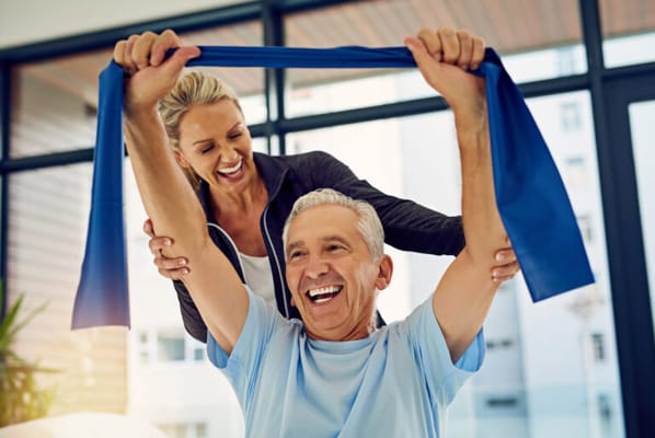 Elderly man exercising with a staff member's assistance