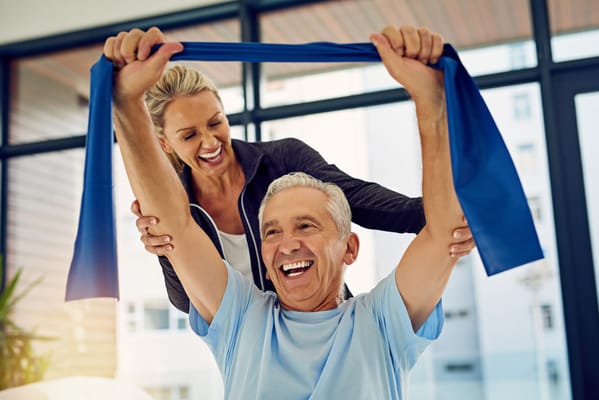 Elderly man exercising with a staff member's assistance
