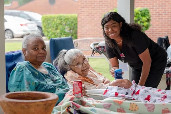 Two residents relaxing outdoors with a staff member