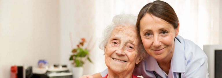 A caregiver smiling with a resident in a cozy room