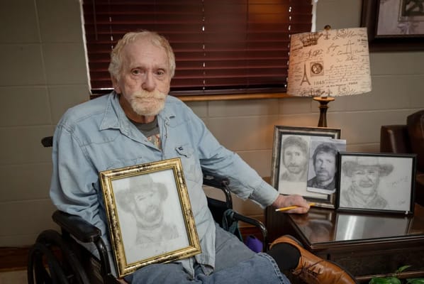 Resident showing framed drawings in a cozy lounge