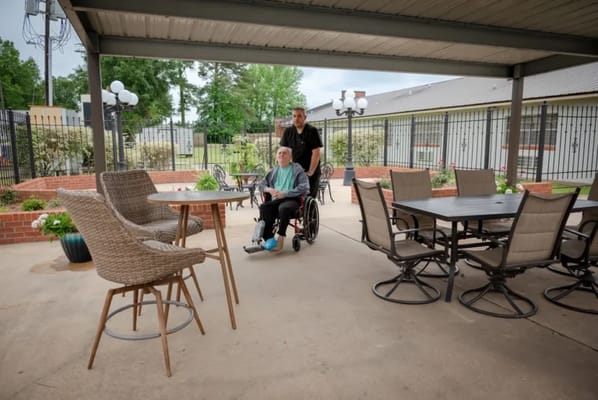 A caregiver assisting a resident in a wheelchair outdoors