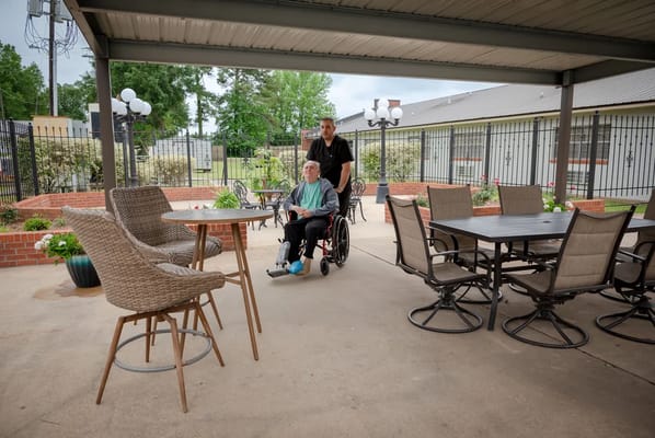 A caregiver assisting a resident in a wheelchair outdoors