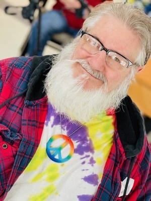 Senior man smiling with colorful clothing and necklace