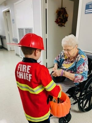 A child dressed as a firefighter gives candy to a resident