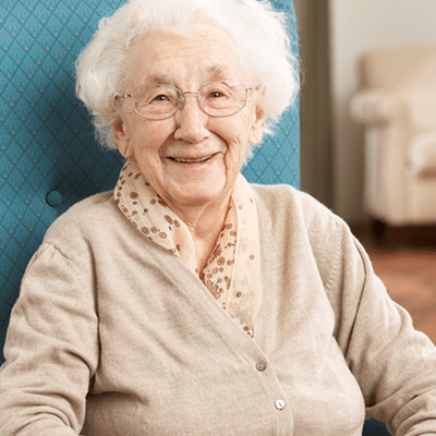 A smiling elderly woman sitting in a chair