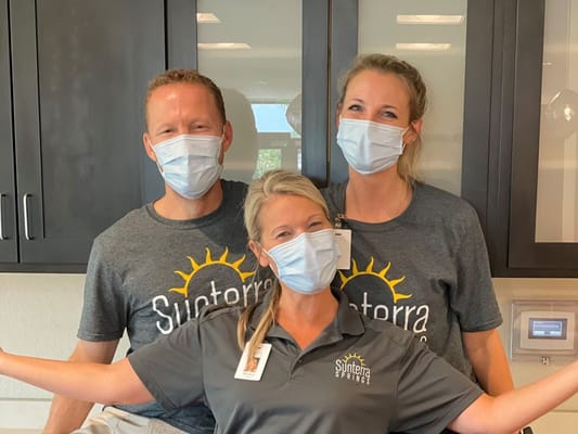 Three staff members smiling and posing together