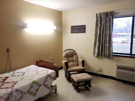 Cozy resident room with chair and quilted bed