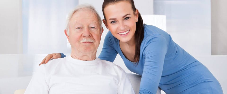 Senior man with caregiver smiling together
