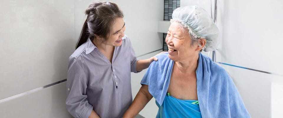 Caregiver assisting a smiling elderly resident