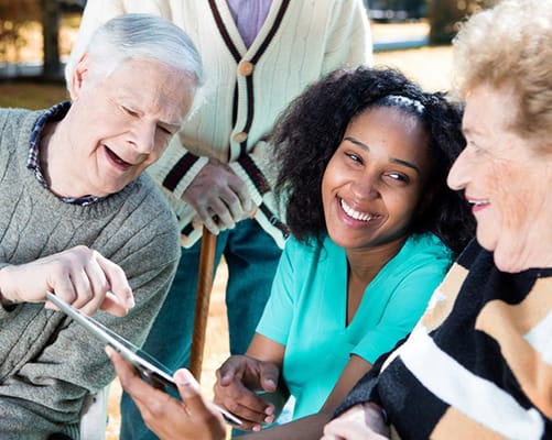 Residents and staff engaging outdoors with a tablet