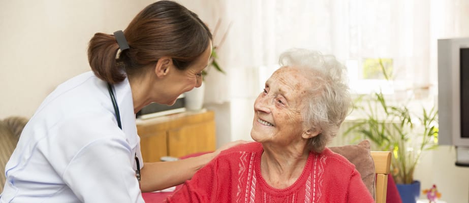 Care staff assisting a smiling elderly resident