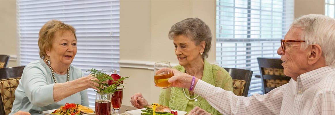 Residents enjoying a meal and toasting in the dining room