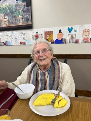 A resident enjoying an omelet in a dining area