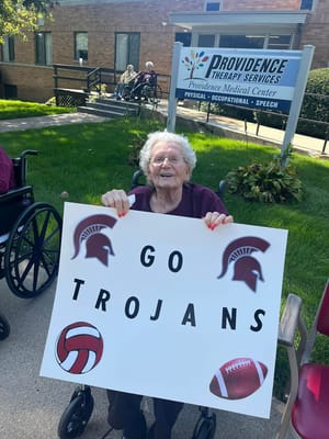 Resident holding a sports sign outside with building in background