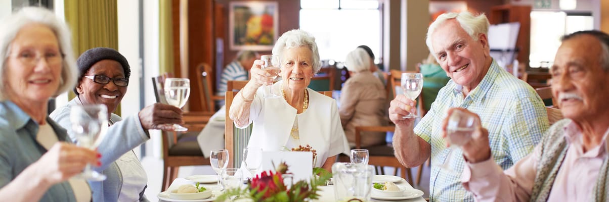 Residents toasting during a meal in the dining room