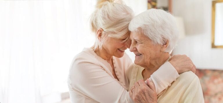 Two women embracing with smiles in a bright interior setting