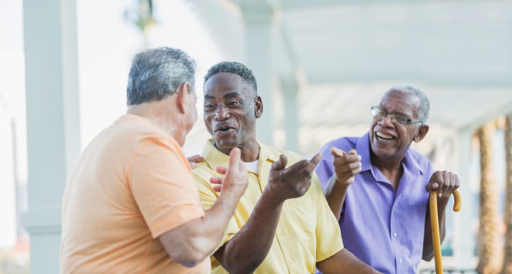 Three seniors chatting outdoors under a covered area