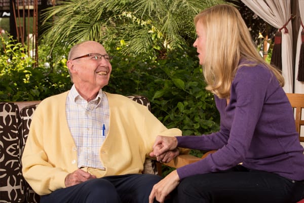 A senior resident interacting with a caregiver in a garden setting