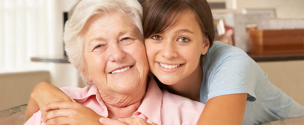 A smiling grandmother and granddaughter embrace