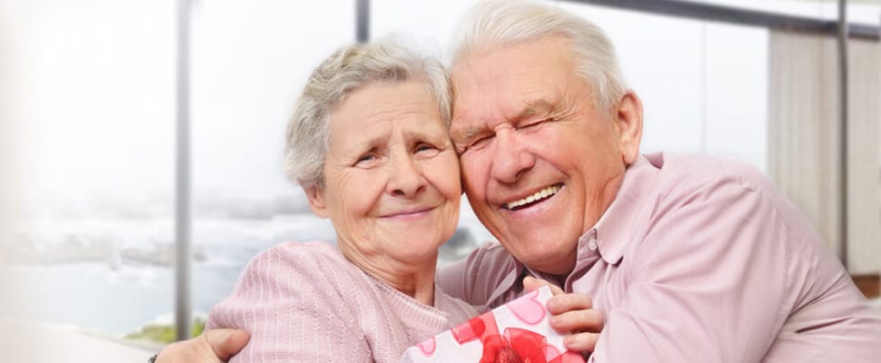 Happy senior couple embracing by a window