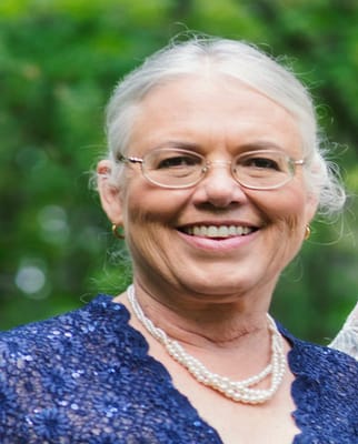 A smiling senior woman wearing pearl jewelry outdoors