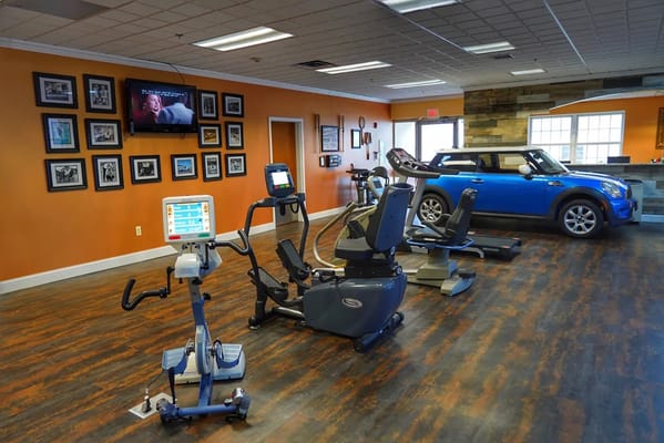 Fitness area with exercise equipment and a blue car