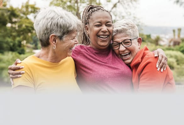 Three women smiling and embracing outdoors