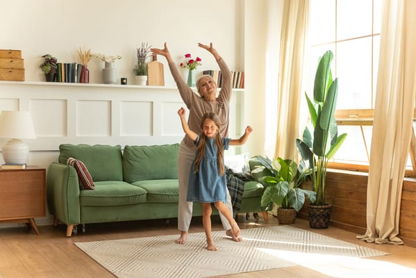 A woman and girl dancing joyfully in a living room