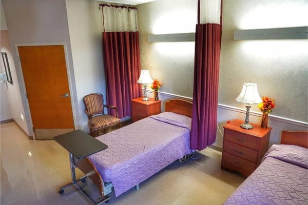 A shared resident room with two beds and lamps