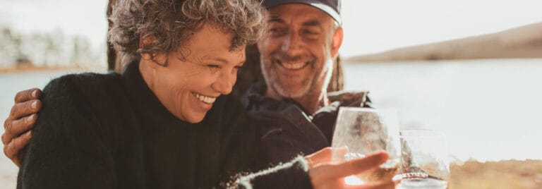 Two smiling seniors enjoying outdoor time by the water