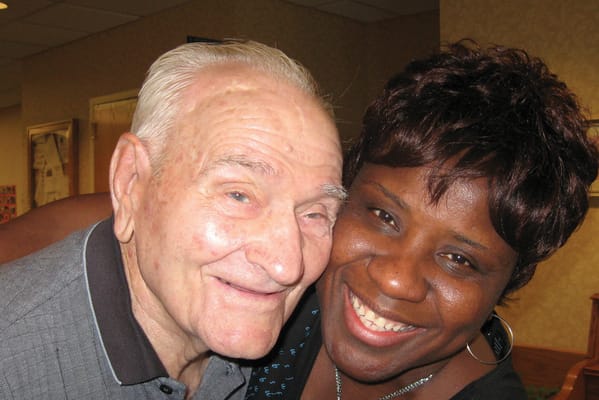 Senior resident and staff member happily posing together