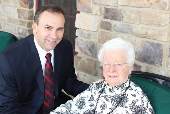 A senior resident posing with a staff member outdoors